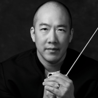 black and white photo of a balding Asian man holding a baton
